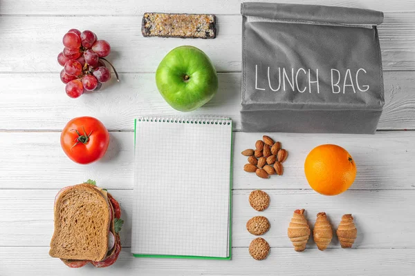 Food for schoolchild, lunch bag and notebook on wooden background — Stock Photo, Image