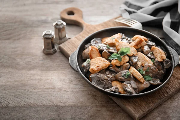 Сковородка с вкусными грибами и мясом на столе — стоковое фото