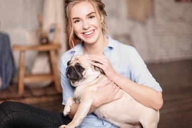 Genç kadın ile şirin pug köpek evde. Evde beslenen hayvan evlat edinmek