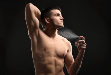 Yakışıklı adam koyu arka plan üzerinde parfüm şişe