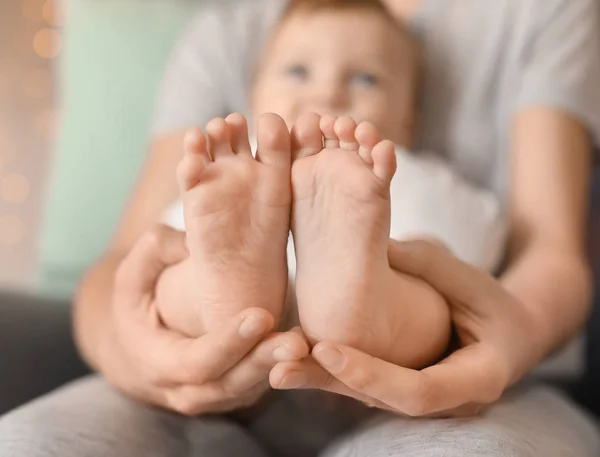 Ung mamma håller fötter av hennes kärleksfulla baby i händer — Stockfoto