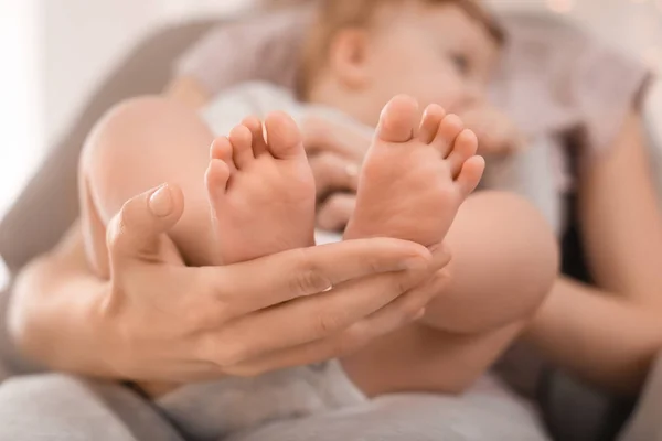 Ung mamma håller fötter av hennes kärleksfulla bebis i hand — Stockfoto