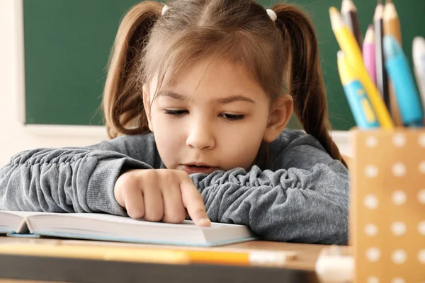 Милая маленькая девочка делает домашнее задание в классе — стоковое фото