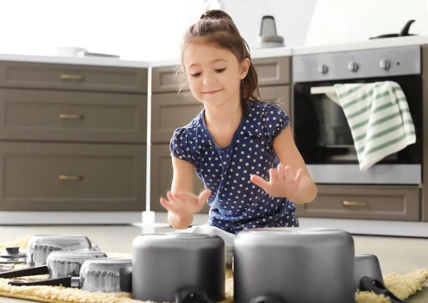 Söt liten flicka som leker med köksutrustning som trummor i köket — Stockfoto