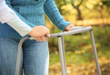 Senior woman with walking frame and young caregiver, closeup clipart
