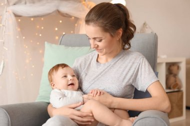 Genç anne ile evde koltukta oturan onun şirin bebek