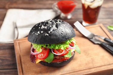 Ahşap tahta üzerinde siyah topuz ile lezzetli burger