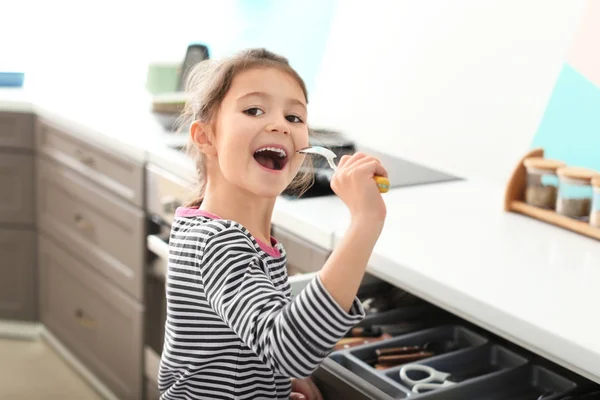 Carino bambina firma canzone in cucchiaio in cucina — Foto Stock