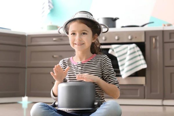 Cute little girl playing with saucepan as drum indoors — Stock Photo, Image