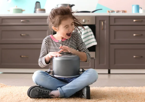 Cute little girl playing with saucepan as drum indoors — Stock Photo, Image