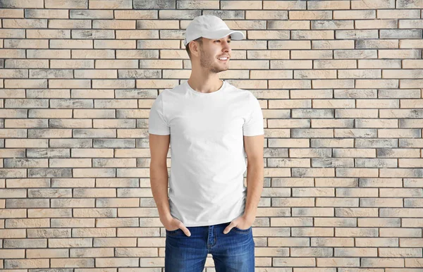 穿着时髦的 T恤衫的年轻人在砖墙上 设计样机 — 图库照片