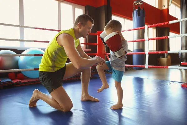 Little boy training with coach in boxing ring