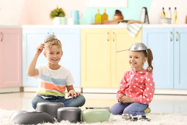 Schattige kleine kinderen spelen met keukengerei thuis — Stockfoto