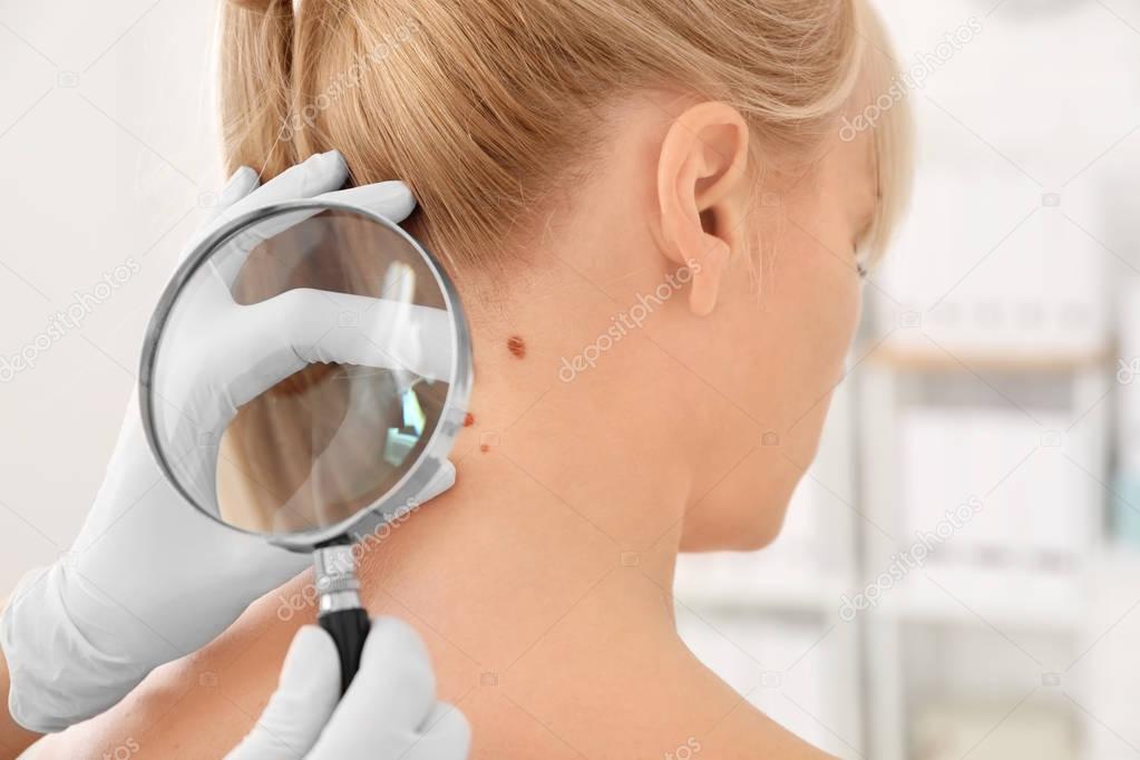 Oncologist examining female patient with magnifier in clinic. Cancer awareness