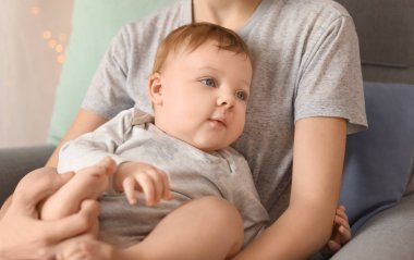 Genç anne ile evde koltukta oturan onun şirin bebek