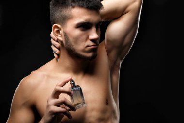 Yakışıklı adam koyu arka plan üzerinde parfüm şişe