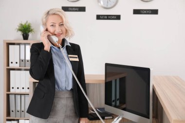 Kadın resepsiyonist otel telefonda konuşuyor