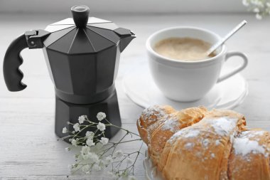 Taze kruvasan, moka pot fincan kahve ve masaya çiçek ile. Lezzetli kahvaltı