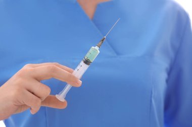 Doktor elinde şırınga tutuyor.