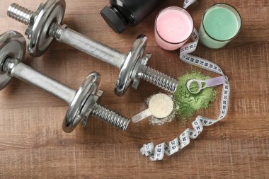 Farklı protein tozu, sarsıntı ve ahşap arka plan üzerinde dumbbells ile kompozisyon