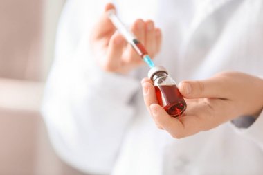 Doktor elinde şırınga tutuyor.