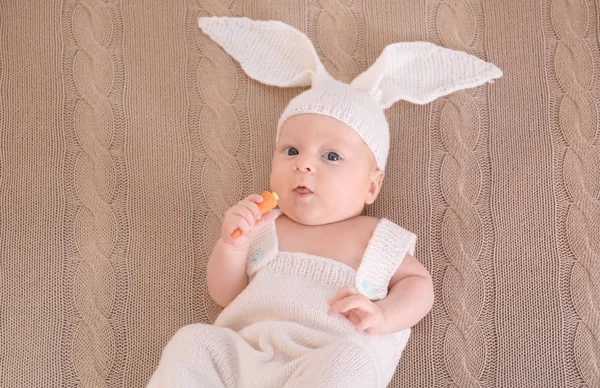 Lindo bebé en traje de conejito con zanahoria acostado en cuadros, vista superior — Foto de Stock