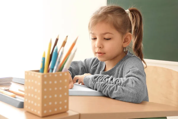 Söt liten flicka göra läxor i klassrummet — Stockfoto