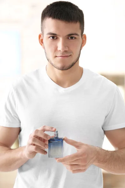 Handsome man with bottle of perfume at home — Stock Photo, Image