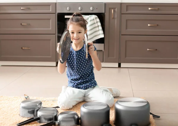 Linda niña jugando con utensilios de cocina como tambores en la cocina — Foto de Stock
