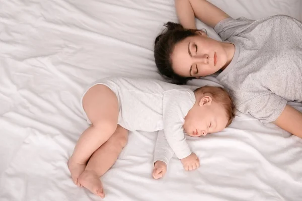 Mãe com seu bebê dormindo na cama em casa — Fotografia de Stock