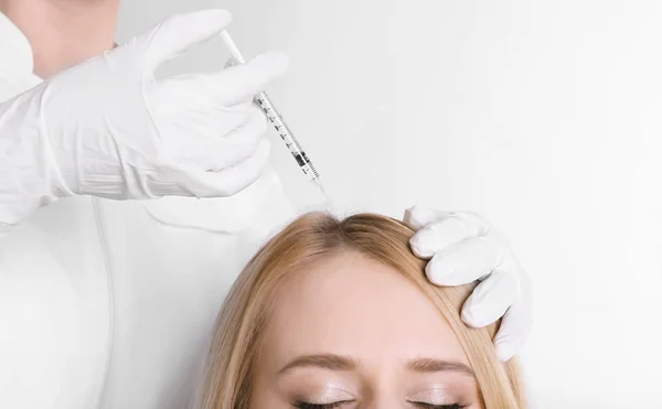 Mulher jovem com problema de cabelo recebendo injeção em fundo claro, close-up — Fotografia de Stock