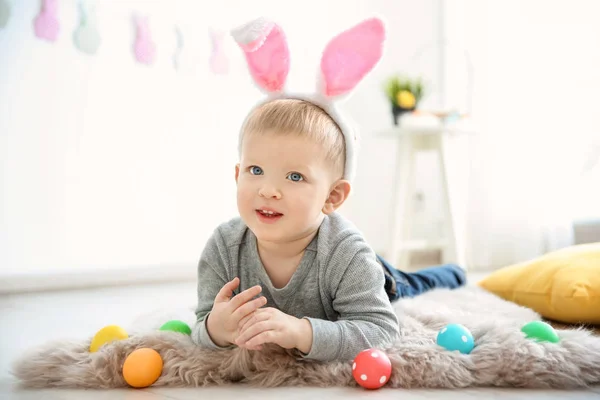 Menino bonito com orelhas de coelho e ovos de Páscoa dentro de casa — Fotografia de Stock