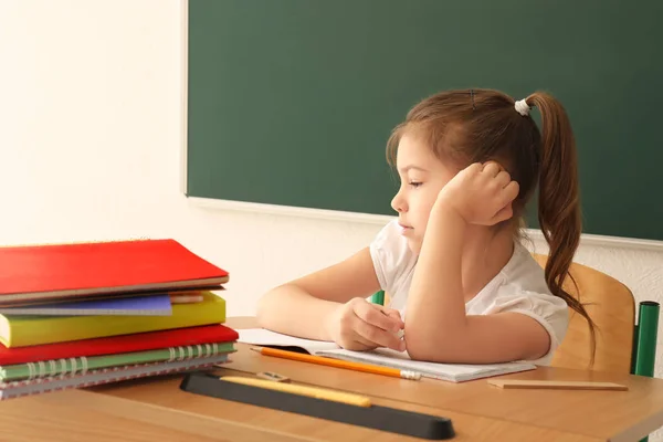 Liten flicka ovilliga att göra läxor i klassrummet — Stockfoto