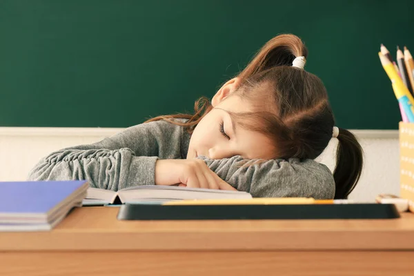 Sleeping little girl tired of doing homework in classroom — Stock Photo, Image