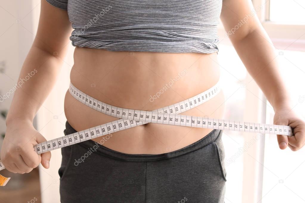 Overweight boy measuring waist 