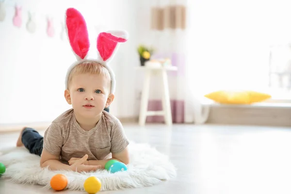 Cute little boy with bunny ears and Easter eggs indoors — Stockfoto