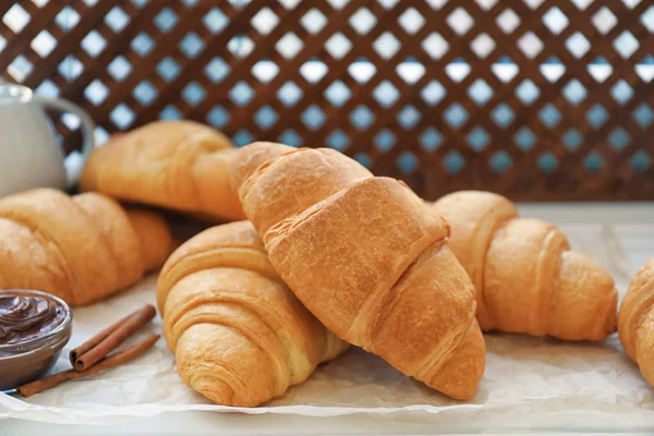 Muitos croissants saborosos e pasta de chocolate na mesa — Fotografia de Stock