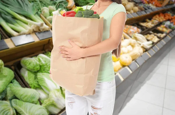 Νεαρή γυναίκα κρατώντας χαρτί τσάντα με είδη παντοπωλείου μετά από ψώνια στο σούπερ μάρκετ — Φωτογραφία Αρχείου