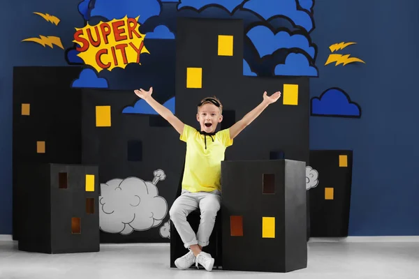 Cute boy as superhero against decoration. Comic strip city theme
