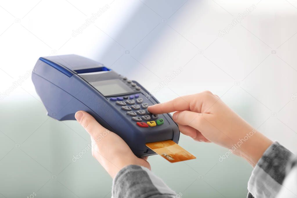 Woman using bank terminal for credit card payment indoors