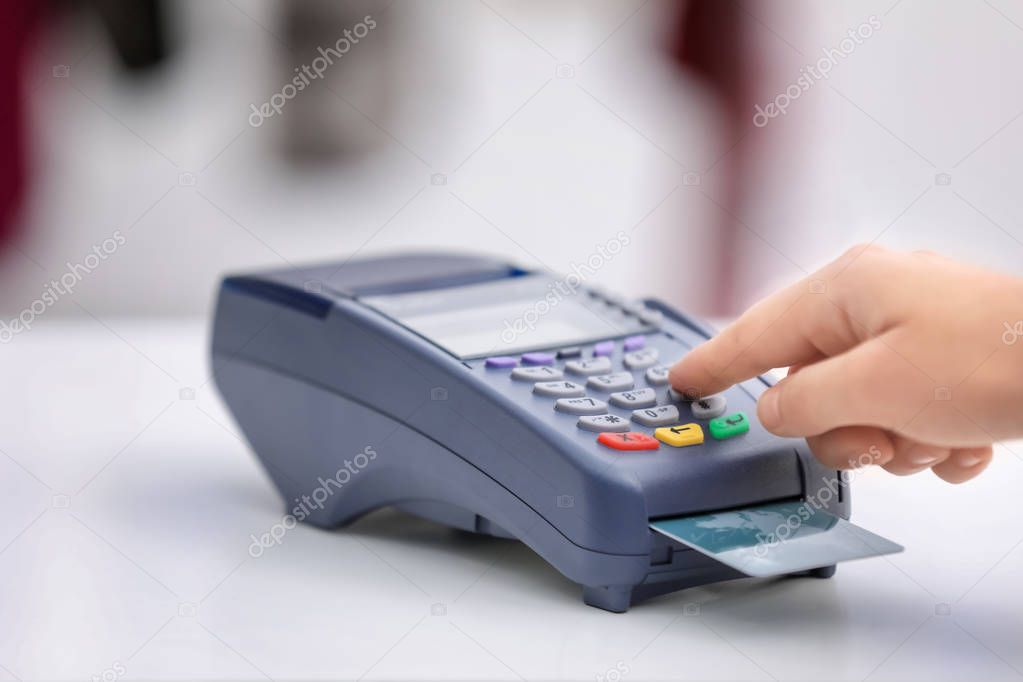 Woman using bank terminal for credit card payment at table