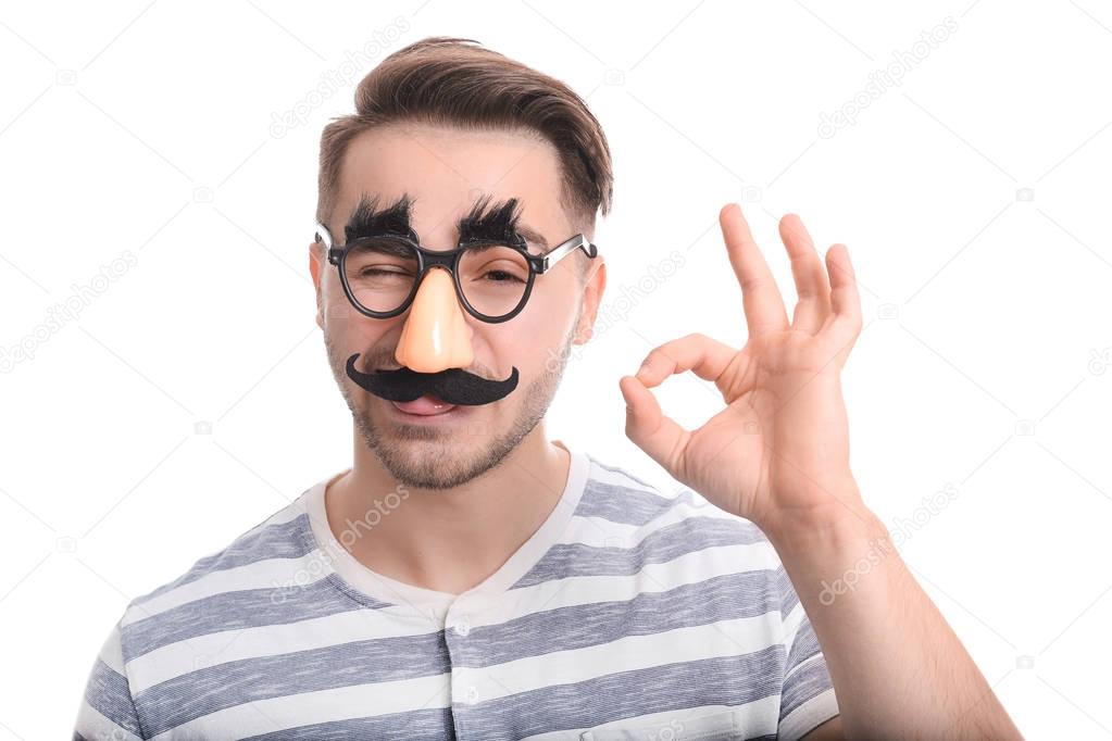 Young man in funny glasses on white background. April fool's day celebration