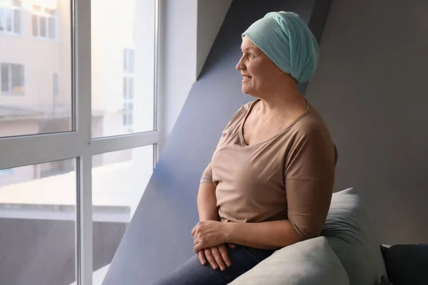 Moden kvinde med kræft i tørklæde indendørs - Stock-foto