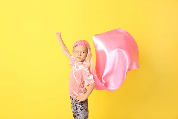 Cute girl in superhero costume on color background — Stock Photo, Image