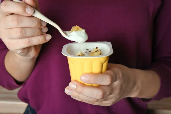 Женщина ест йогурт с кусочками банана в помещении, крупным планом — стоковое фото