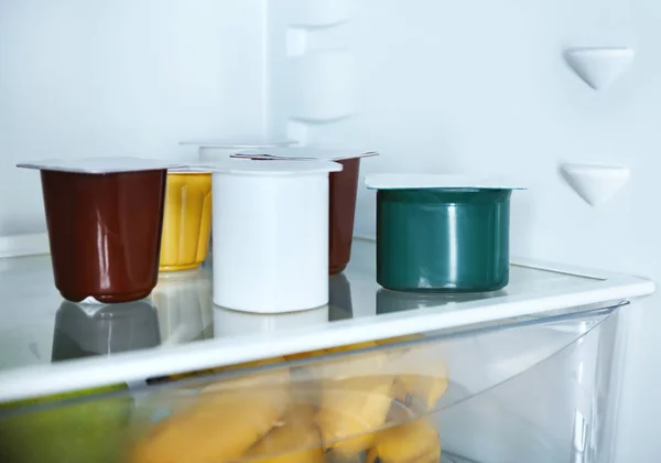 Plastic cups with yogurt in refrigerator — Stock Photo, Image