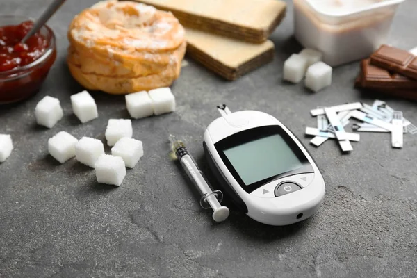 Digitales Glukometer und Süßigkeiten auf dem Tisch. Diabetes-Konzept — Stockfoto