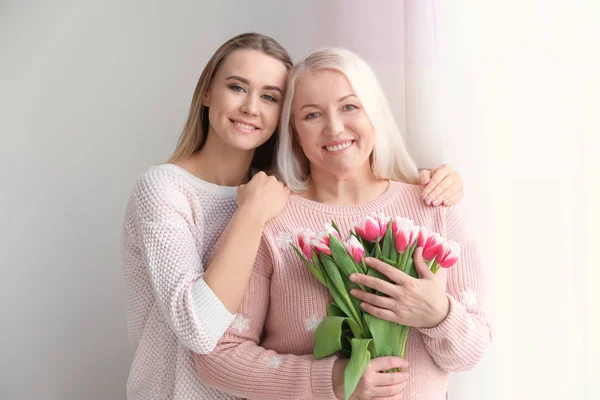 Jonge dochter en moeder met boeket bloemen thuis — Stockfoto