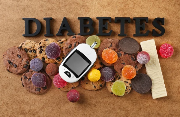 Sammansättning med ordet ”Diabetes”, sötsaker och digitala Glukometer på färgbakgrund — Stockfoto