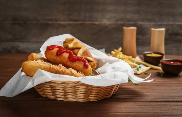 Tasty corn dogs with sauces in basket — Stock Photo, Image